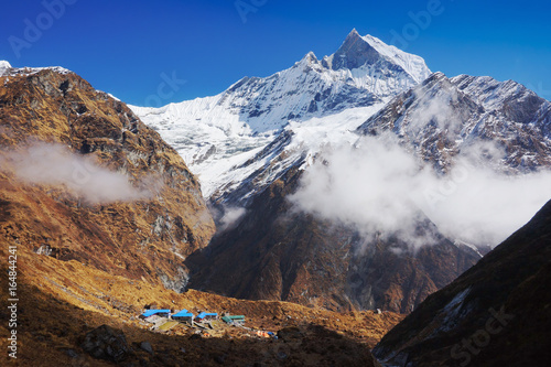 Himalaya mountains. Machapuchare summit and roofs of base camp  or MBC  underneath. View from Annapurna Base Camp trail . Horizontal  landscape. Nepal  Annapurna circuit and ABC trek  Asia.