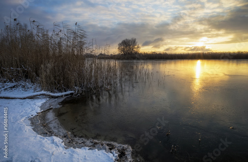 Winter landscape with sunset sky and frozen river. Daybreak