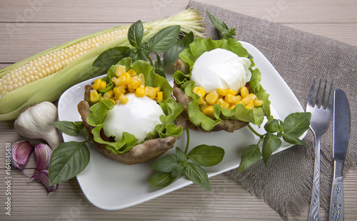 Poached eggs in the basket of bacon with herbs and tomatoes and corn with garlic. On wooden background.