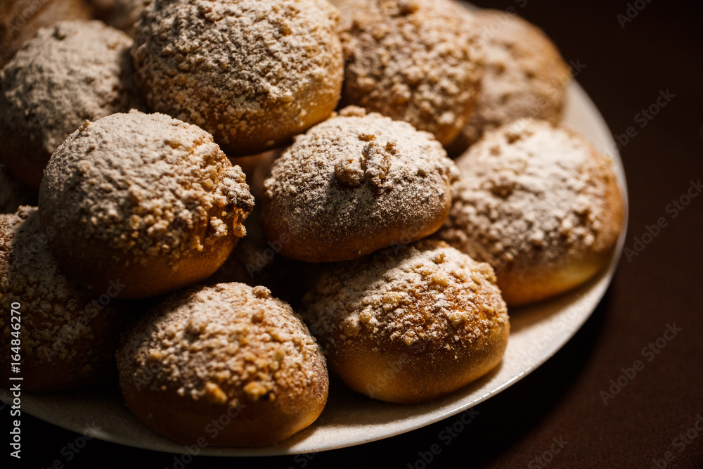 ruddy delicious muffins dusted with powdered sugar on the plate on brown tablecloth