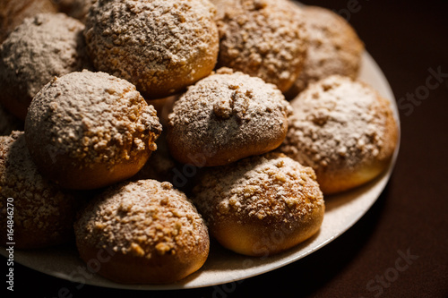ruddy delicious muffins dusted with powdered sugar on the plate on brown tablecloth