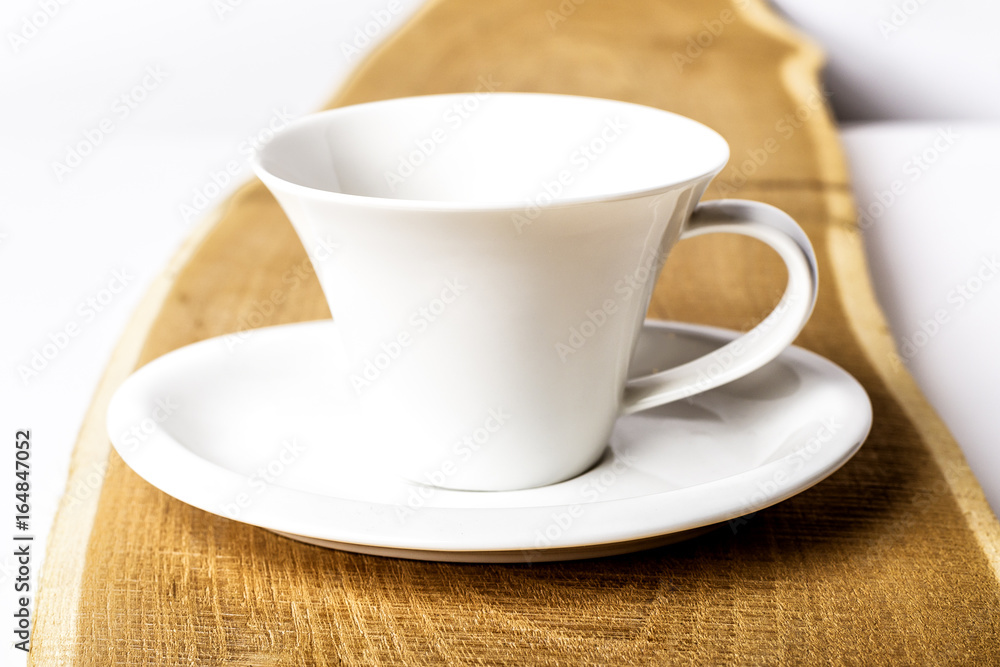one pure white ceramic Cup and saucer stands on a wooden table one pure white ceramic Cup and saucer stands on a wooden table