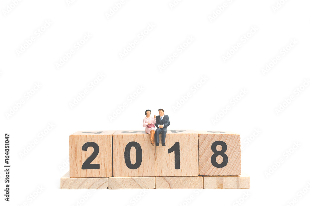 Miniature people business concept sitting on wooden block number 2018