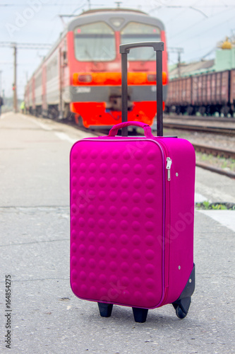 Suitcase bag at railway station with the train as background.