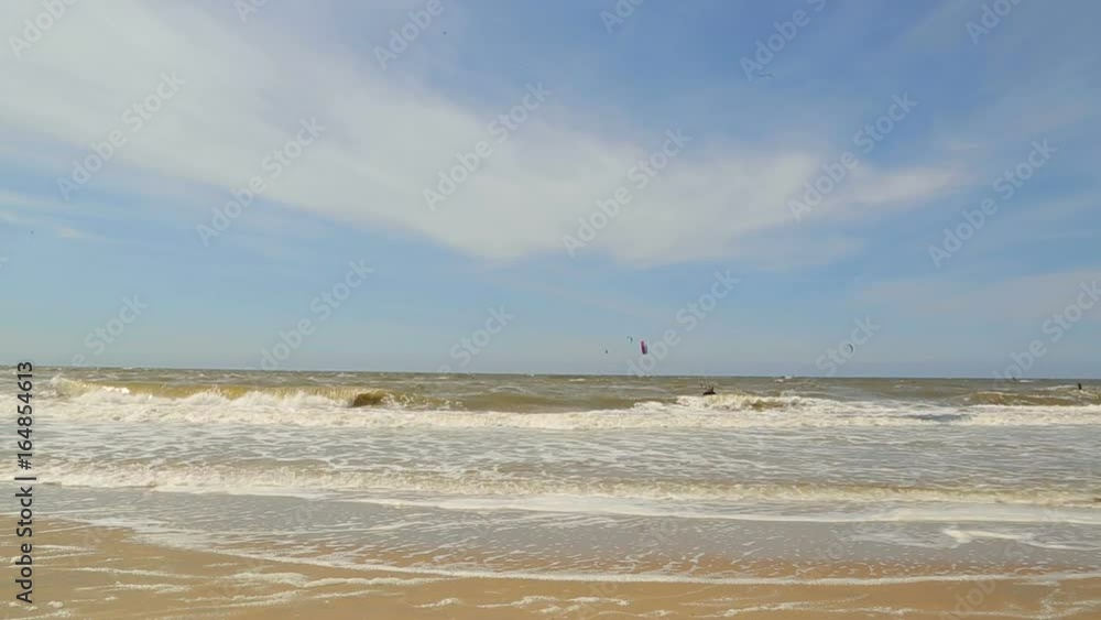 Kitesurfing. The waves of the north Sea are rolled on a sandy beach. Background of the sea Kitesurfing. The waves of the north Sea are rolled on a sandy beach. Background of the sea