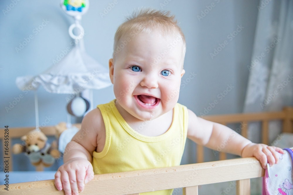 Portrait of funny kid standing up in her crib in the room. Portrait of funny kid standing up in her crib in the room.