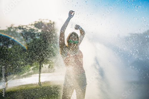 Pretty girl gets wet with water in a park
