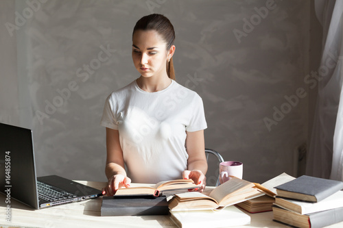 girl is preparing for the exam reading book works at the computer photo