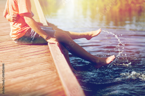 happy teenage couple sitting on river berth