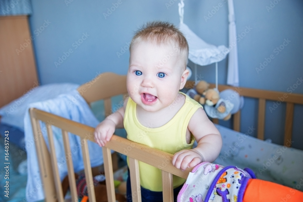 Funny baby standing up in her crib in the room. Funny baby standing up in her crib in the room.