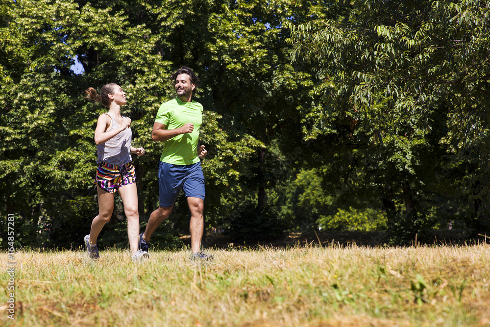 Fototapeta premium Young couple running in the park on a sunny day