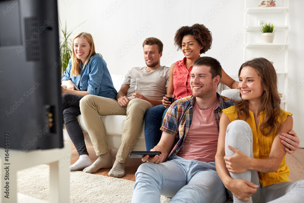 happy friends with remote watching tv at home happy friends with remote watching tv at home