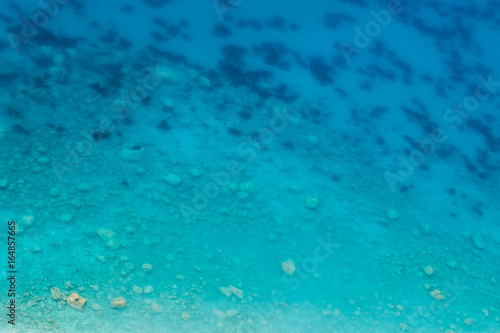 Transparent clean sea water off the coast, a gradient of blue from the beach to the depth for background, aerial view