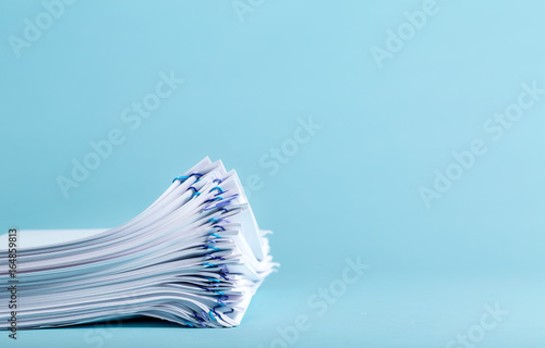 Pile of papers organized with paper clips on a blue background photo