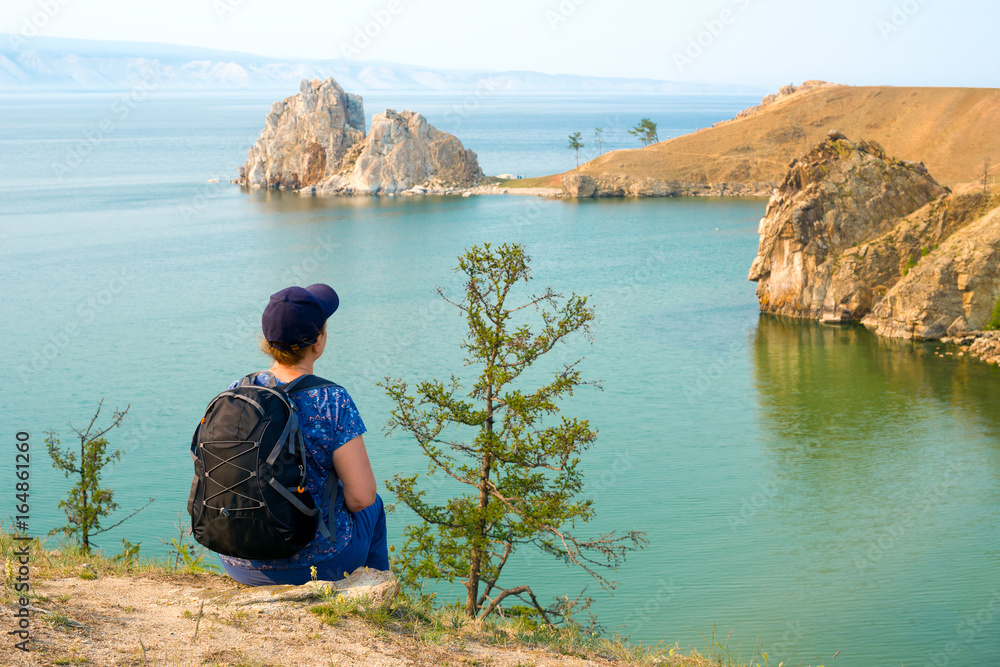 Lake Baikal, Siberia, Russia. A woman backpacker looks at the Shamanka Rock, Cape Burhan on Olkhon Island 