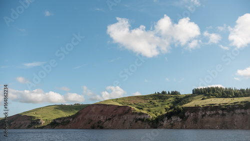 Summer landscape - european river, blue sky and green meadow on coast