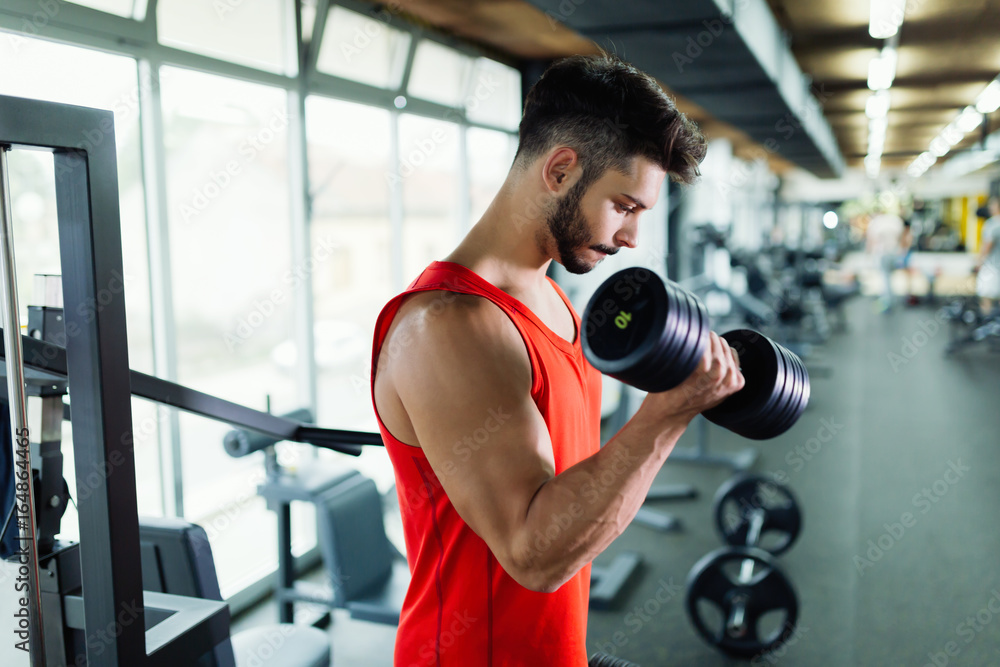Muscular bodybuilder workout in gym doing biceps exercises Muscular bodybuilder workout in gym doing biceps exercises