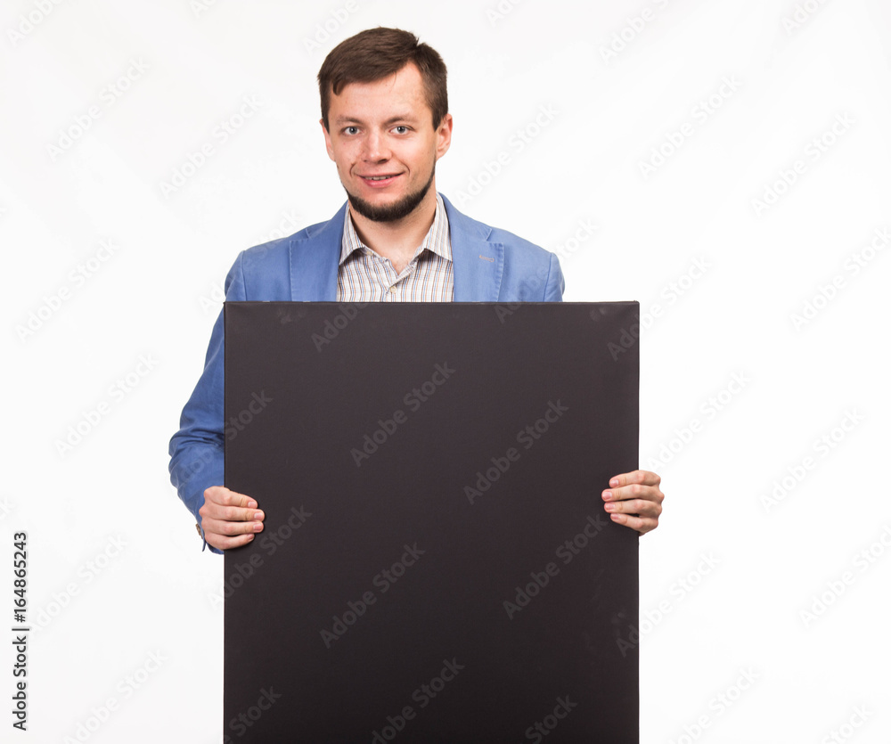 Young happy man portrait of a confident businessman showing presentation, pointing paper placard gray background. Ideal for banners, registration forms, presentation, landings, presenting concept. Young happy man portrait of a confident businessman showing presentation, pointing paper placard gray background. Ideal for banners, registration forms, presentation, landings, presenting concept.