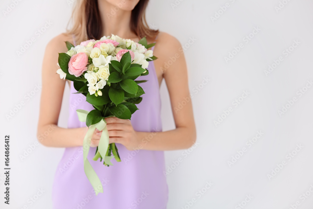 Young woman holding beautiful bouquet with freesia flowers on white background