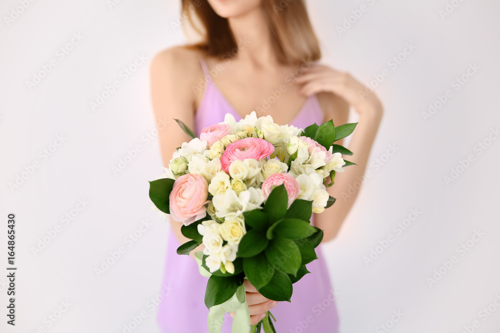 Young woman holding beautiful bouquet with freesia flowers on white background