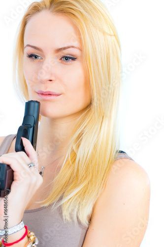 Blonde young woman in short skirt with gun on white background