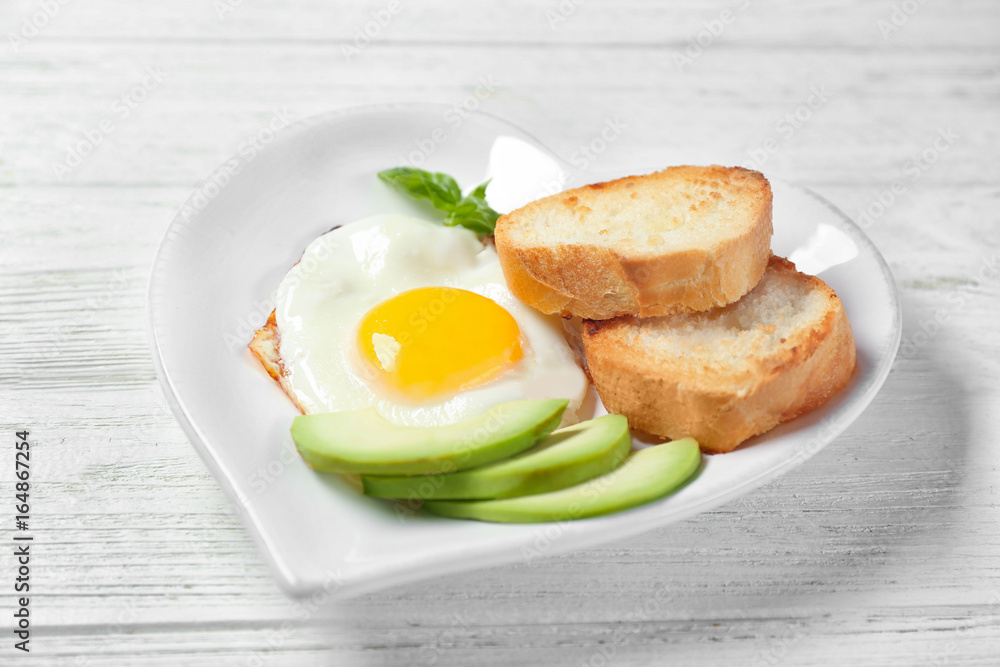 Delicious over easy egg with toasts and avocado on kitchen table Delicious over easy egg with toasts and avocado on kitchen table