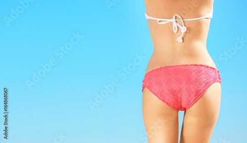Beautiful young woman in bikini and blue sky on background