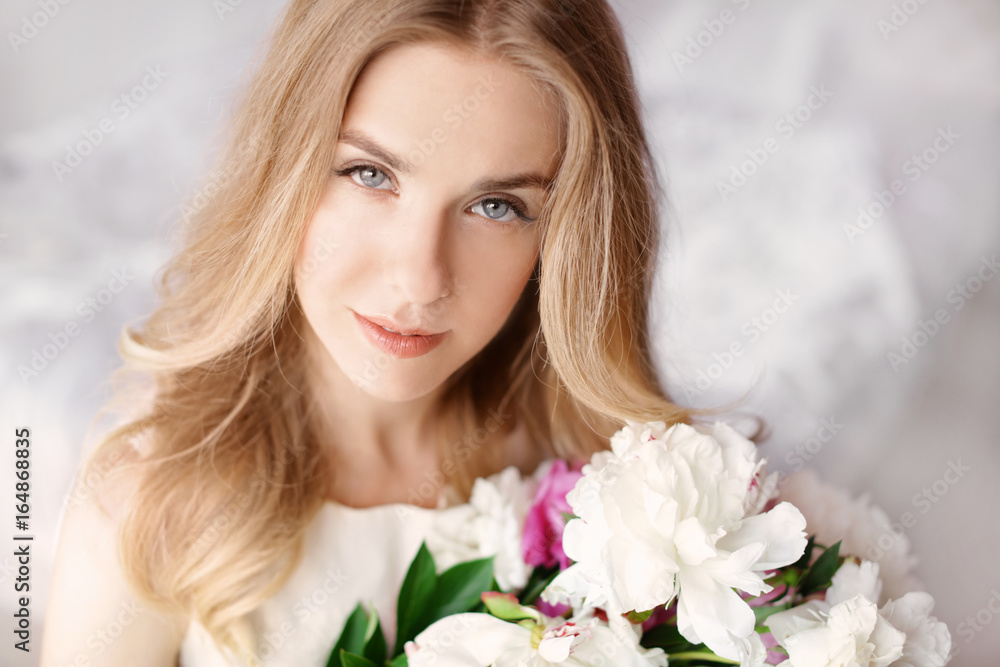 Beautiful young woman with bouquet of peonies, closeup