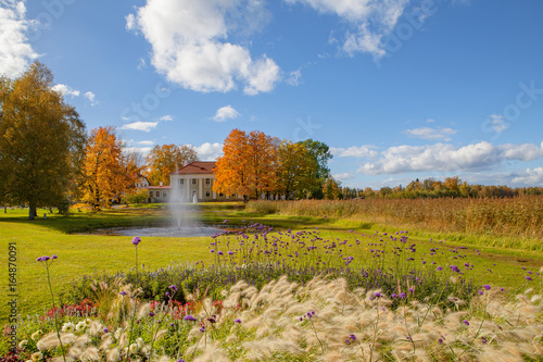 Autumn park with flowers and fountain on the meadow near old manor. Bright fall time. photo