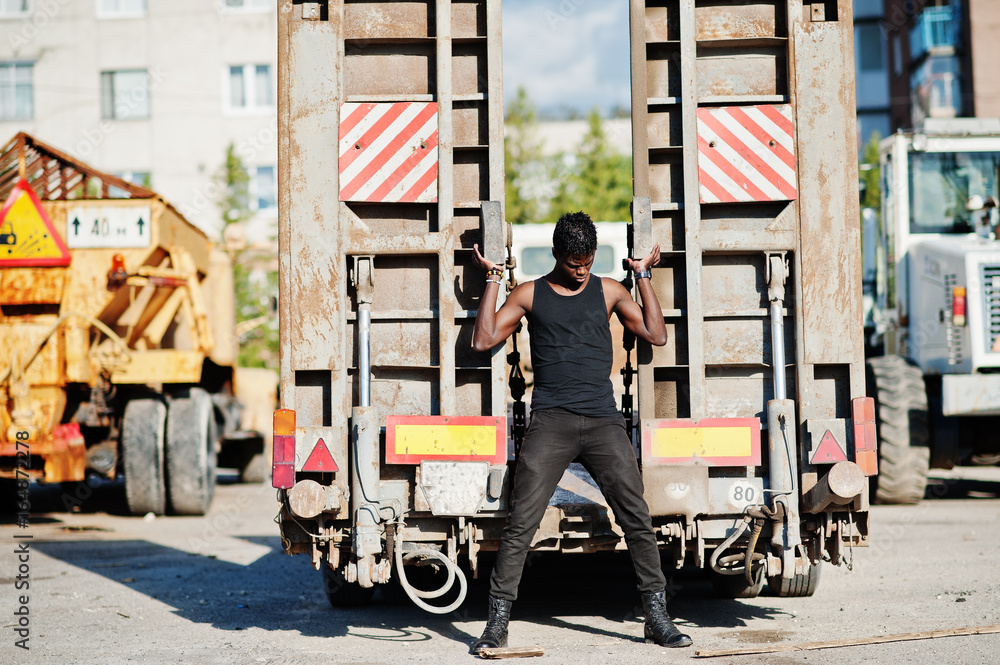 Obraz premium Portrait of an attractive black african american man posing next to the industrial machinery.