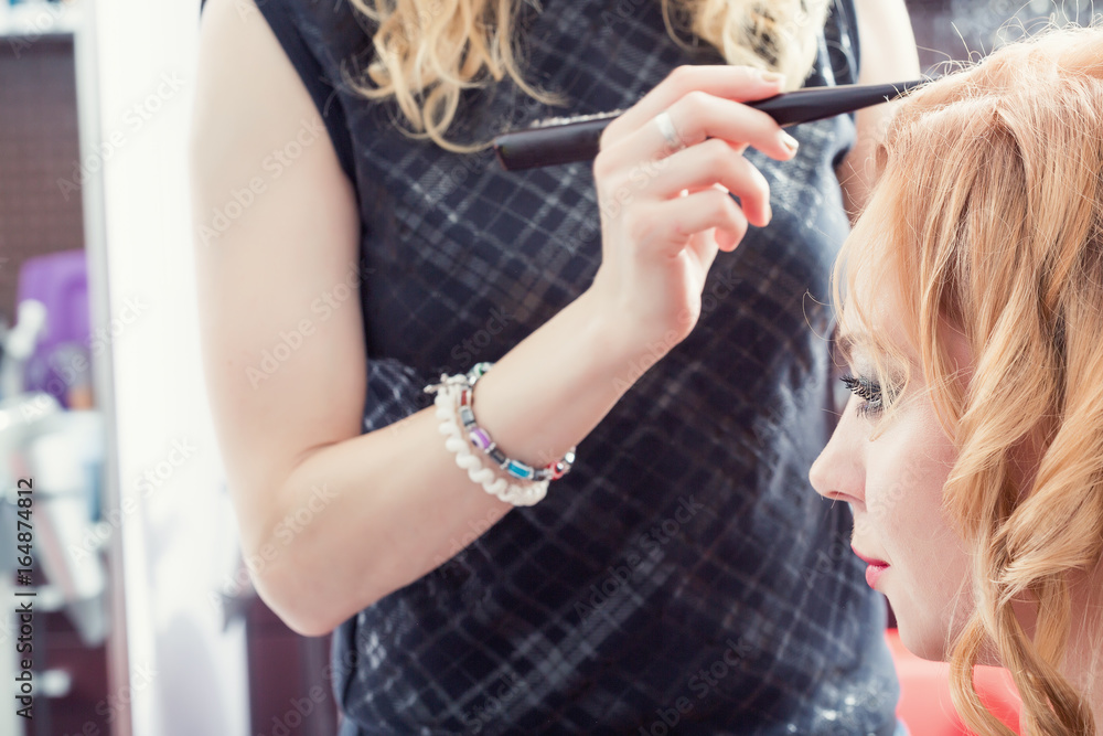 A hairdresser making a haircut for a blonde female client A hairdresser making a haircut for a blonde female client