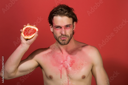 grapefruit in hand ofman with creative fashionable makeup, vitamin photo