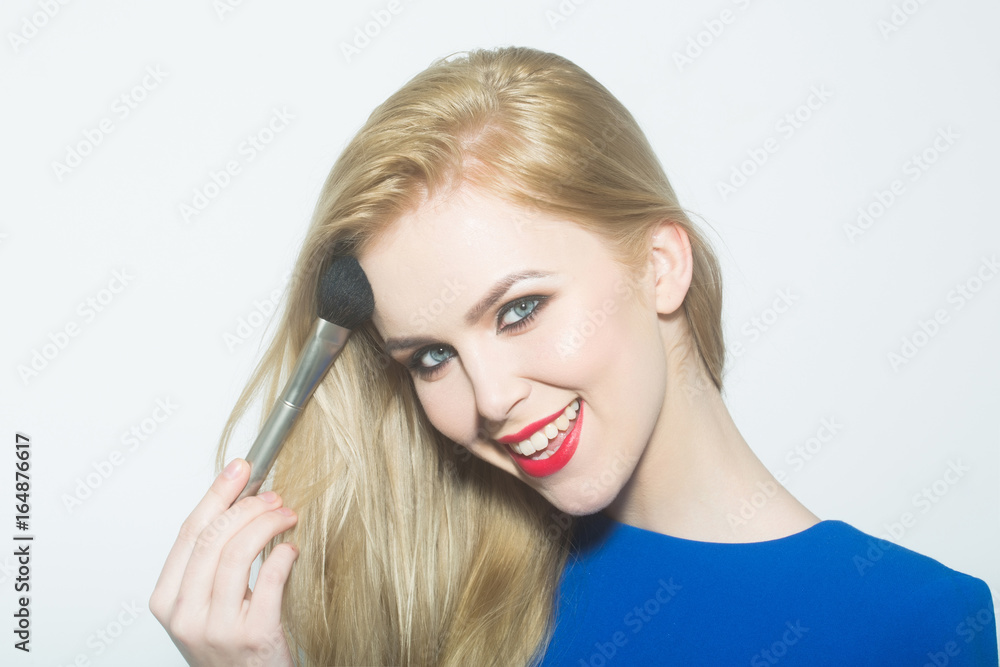 Happy woman applying makeup on face with powder brush Happy woman applying makeup on face with powder brush