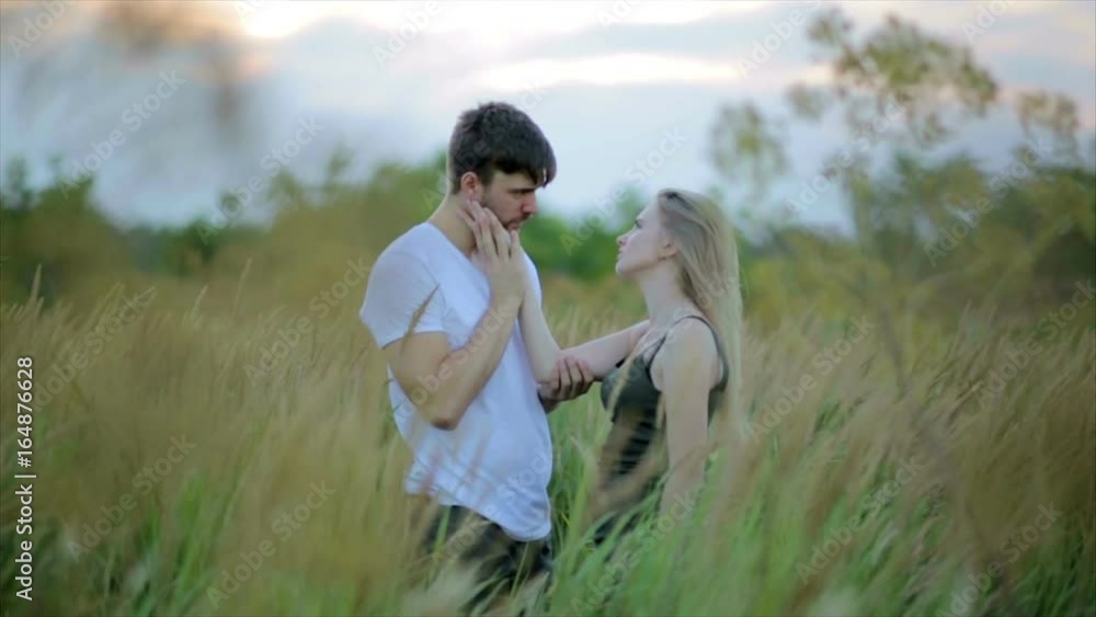 Romantic Couple at Sunset. Two people in love at sunset or sunrise. Man and woman kissing on field Romantic Couple at Sunset. Two people in love at sunset or sunrise. Man and woman kissing on field