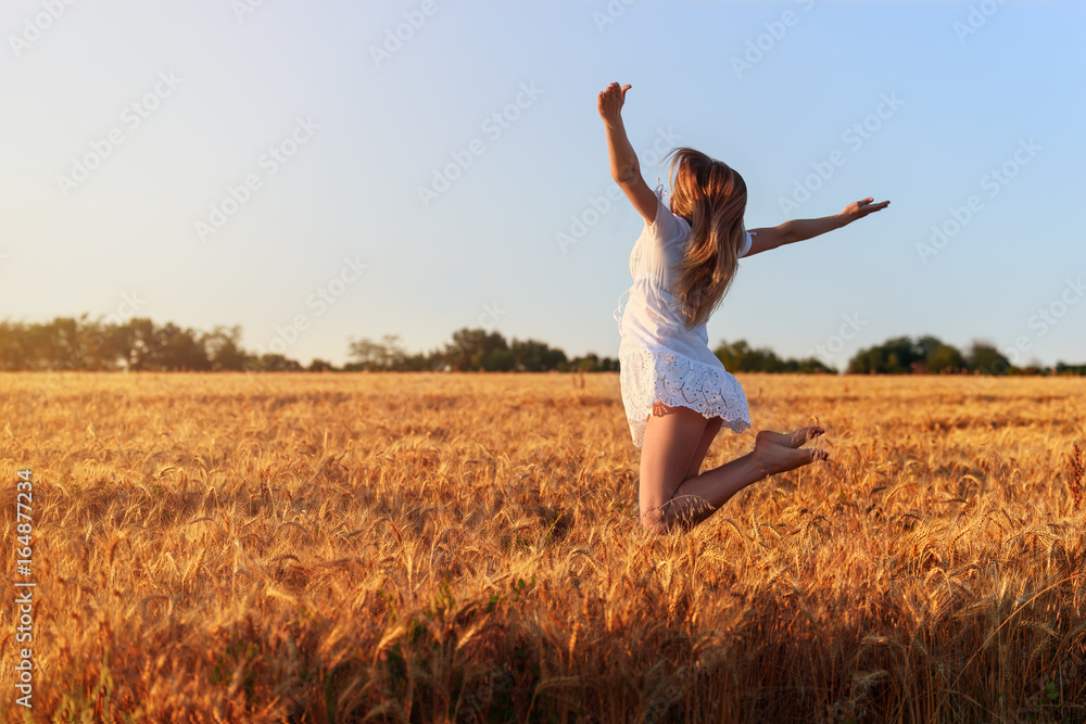 Beautiful young girl in white dress jumping in wheat field Beautiful young girl in white dress jumping in wheat field
