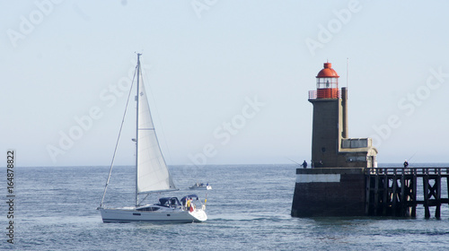 Vue sur un phare en bretagne avec des bateaux qui passent devant