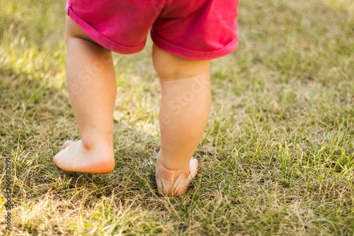 A small child walks barefoot in the grass, close-up.