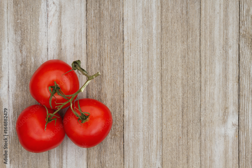 Red vine ripe tomatoes on weathered wood background Red vine ripe tomatoes on weathered wood background