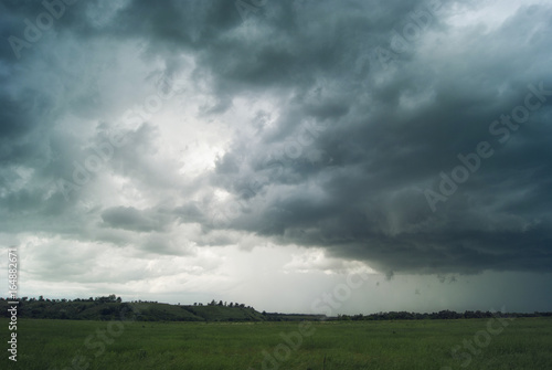 Storm cloud over green fields forests and hills