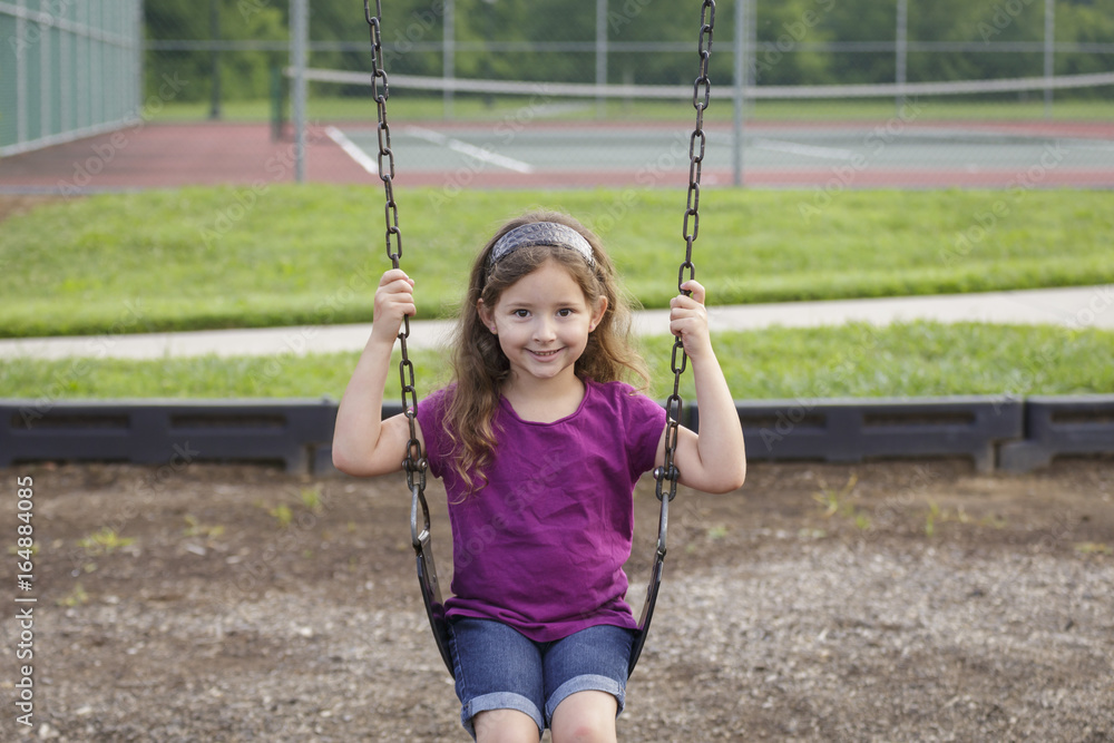 little girl swinging at the playground on a warm summer day little girl swinging at the playground on a warm summer day