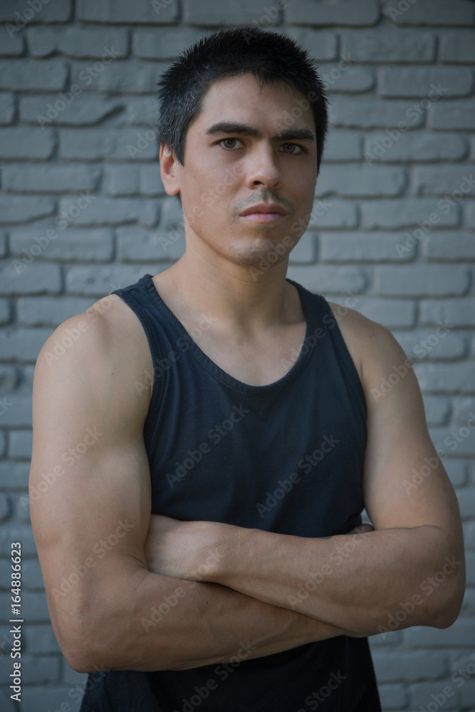 Obraz premium Ethnic Athletic Man in Front of Brick Wall