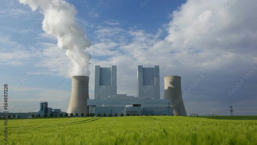 View to a shiny new lignite power station over a green rye field View to a shiny new lignite power station over a green rye field