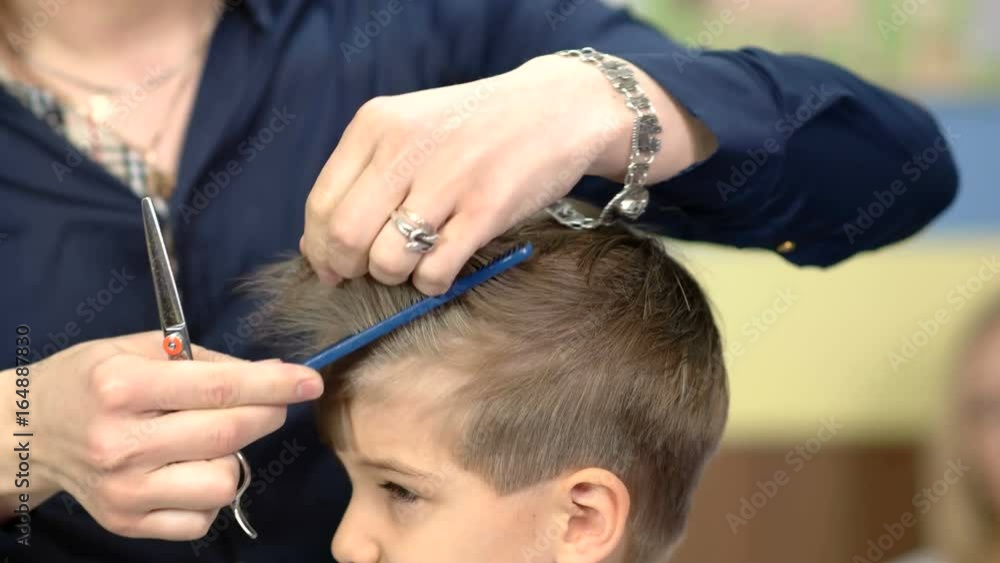 Barber cuts the kid's hair with scissors Barber cuts the kid's hair with scissors