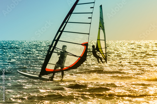 Windsurfing on the background of blue sea at sunset