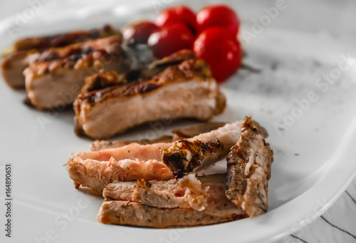 Yummy grilled spare ribs with cherry tomatoes on square white plate