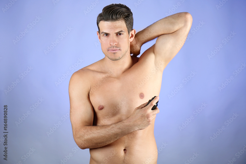 Handsome young man with deodorant on color background