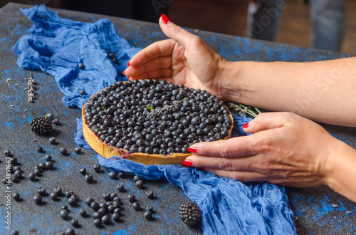 Woman hands holding french homemade tart with blueberries . Top view photo