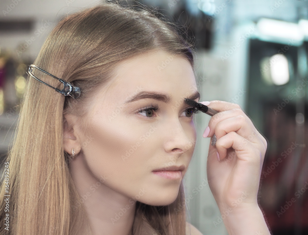 Young girl makes make-up at he eyelashes and looking at the mirror Young girl makes make-up at he eyelashes and looking at the mirror