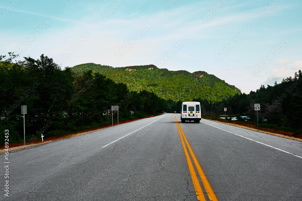 Landschaft und Strasse in den White Mountains New Hampshire mit einem fahrenden Campingmobil und Wald
