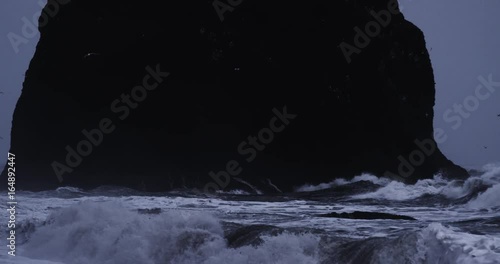 Slow motion, waves crash into rock formation in Iceland